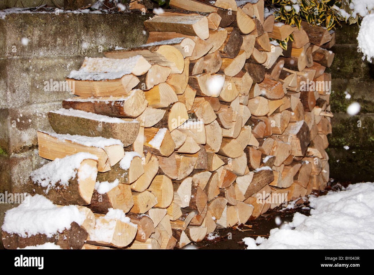 Hölzerne Maschinenbordbücher, Brennholz gestapelt im Schnee, im Schneegestöber Stockfoto