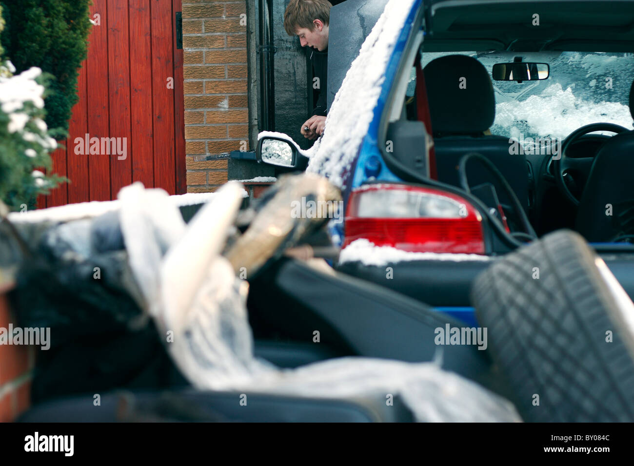 Ein junger Mann, den Kofferraum seines Autos ausräumen einige Arbeiten auf der Innenseite durchgeführt. Stockfoto