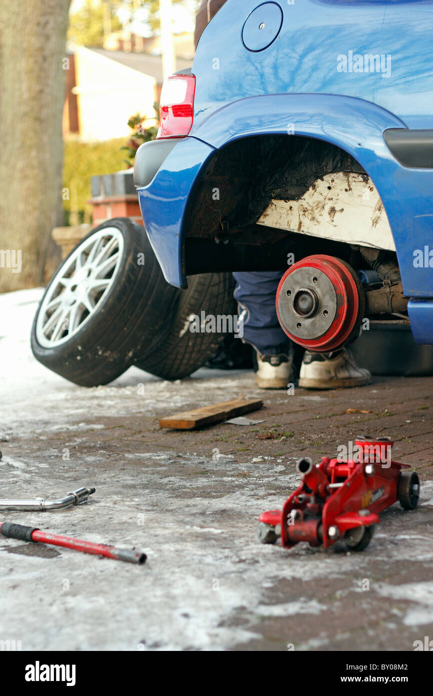 Ein Citroen Saxo aufgehalten von einem Wagenheber mit seiner Rad entfernt, während es unter eisigen Bedingungen repariert wird. Stockfoto