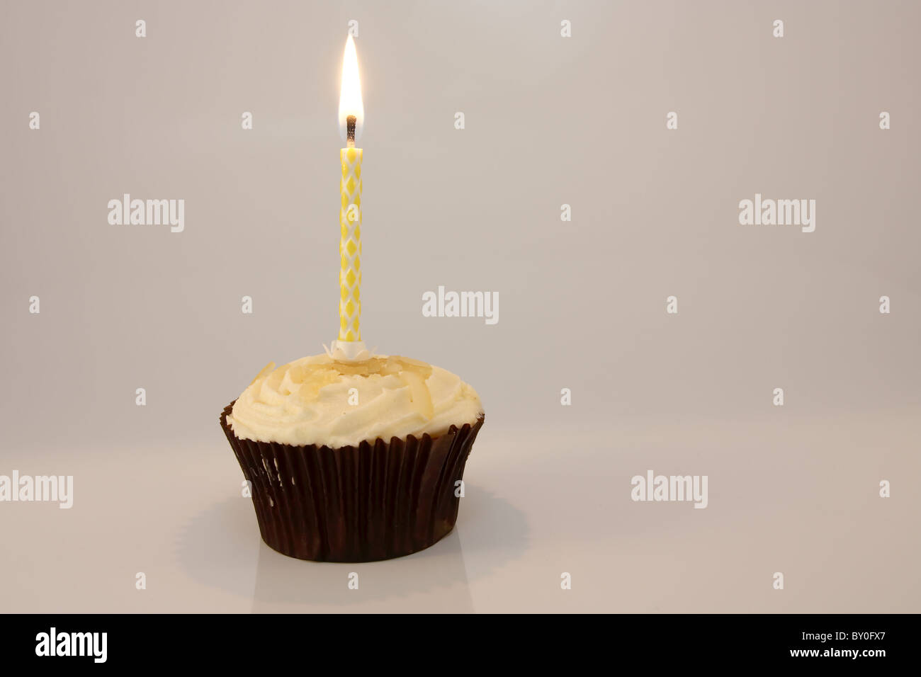 Kerze in Zitrone Cupcake vor einem weißen Hintergrund Stockfoto