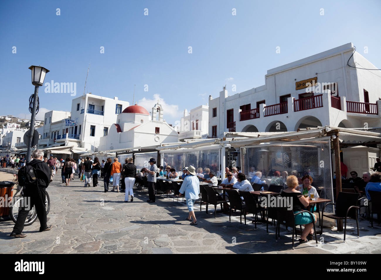Rot-Kuppel-Kirche und Restaurants an der Strandpromenade in Mykonos. Stockfoto