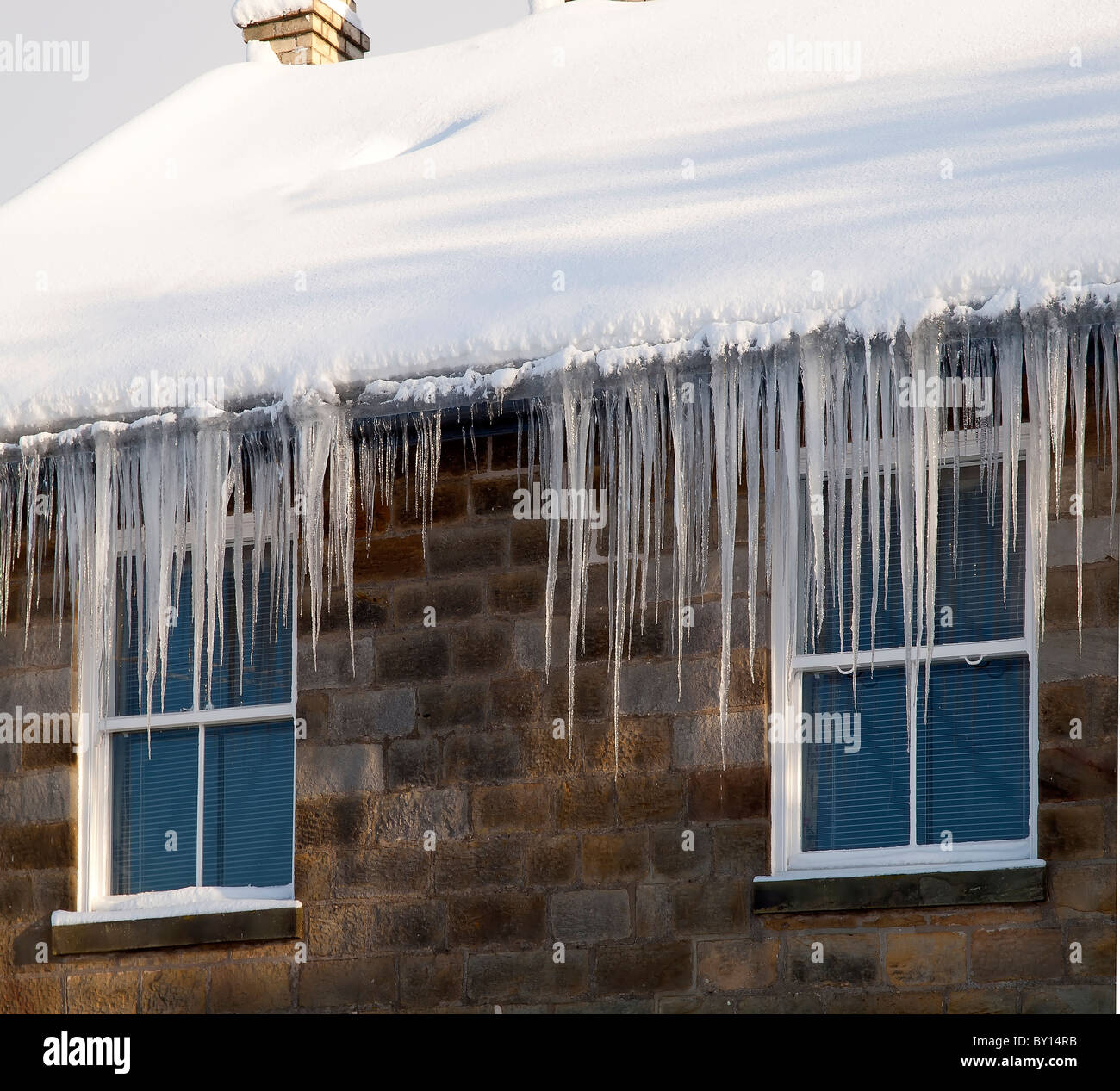 Lange Eiszapfen hängen von Dachrinnen in Goathland North Yorkshire Stockfoto