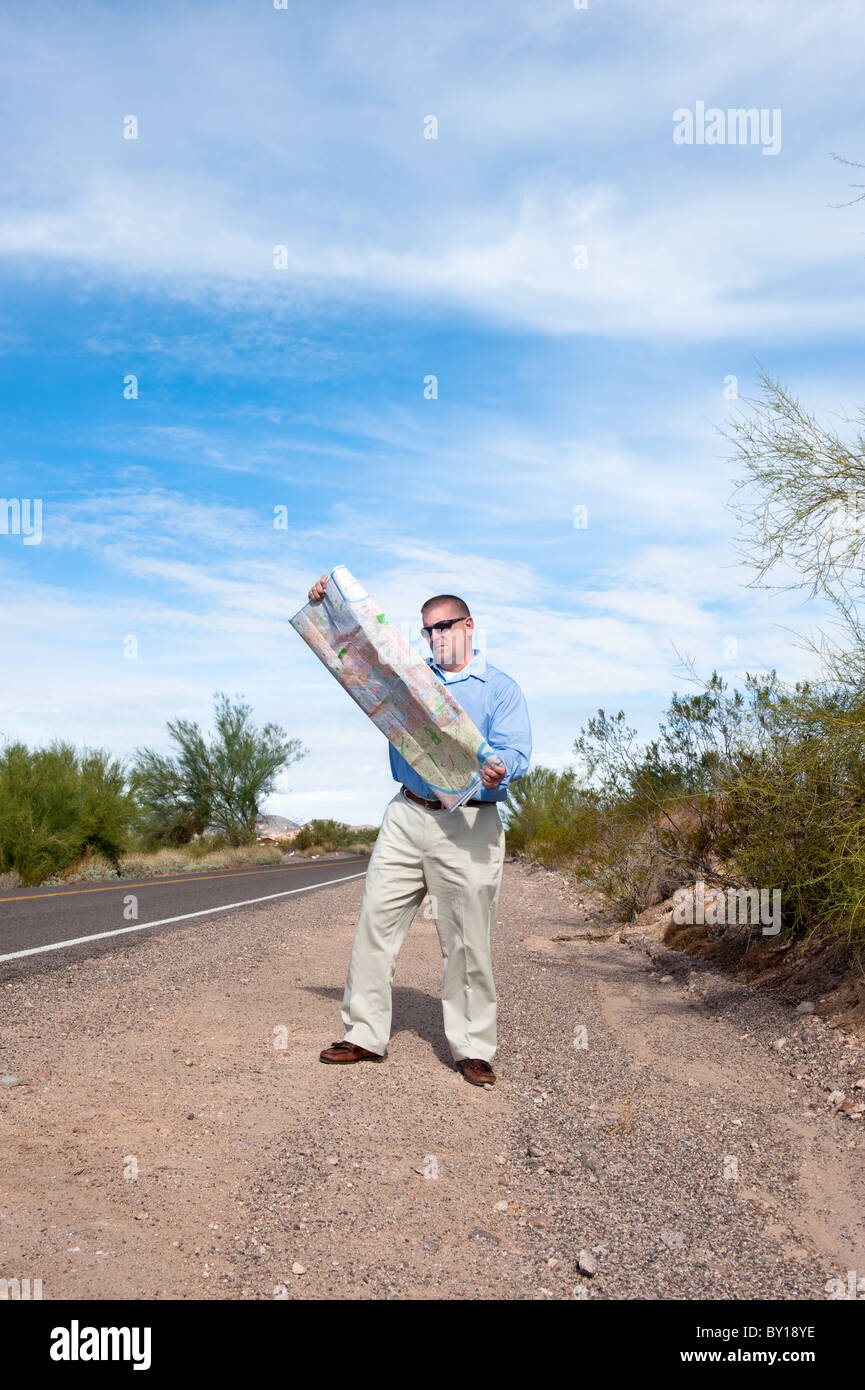 Ein Mann steht auf einer verlassenen Straße einen Fahrplan zu lesen Stockfoto