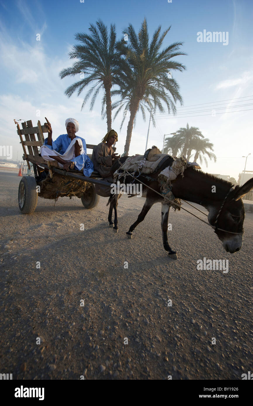 Zwei ägyptische Männer sitzen im Wagen, mit dem Esel auf staubigen Wüste Strecke gezogen Stockfoto