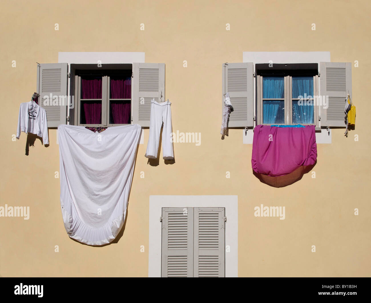 Bettwäsche und Kleidung trocknen hängen aus den Fenstern eines Hauses in einer Straße im Süden Frankreichs Stockfoto