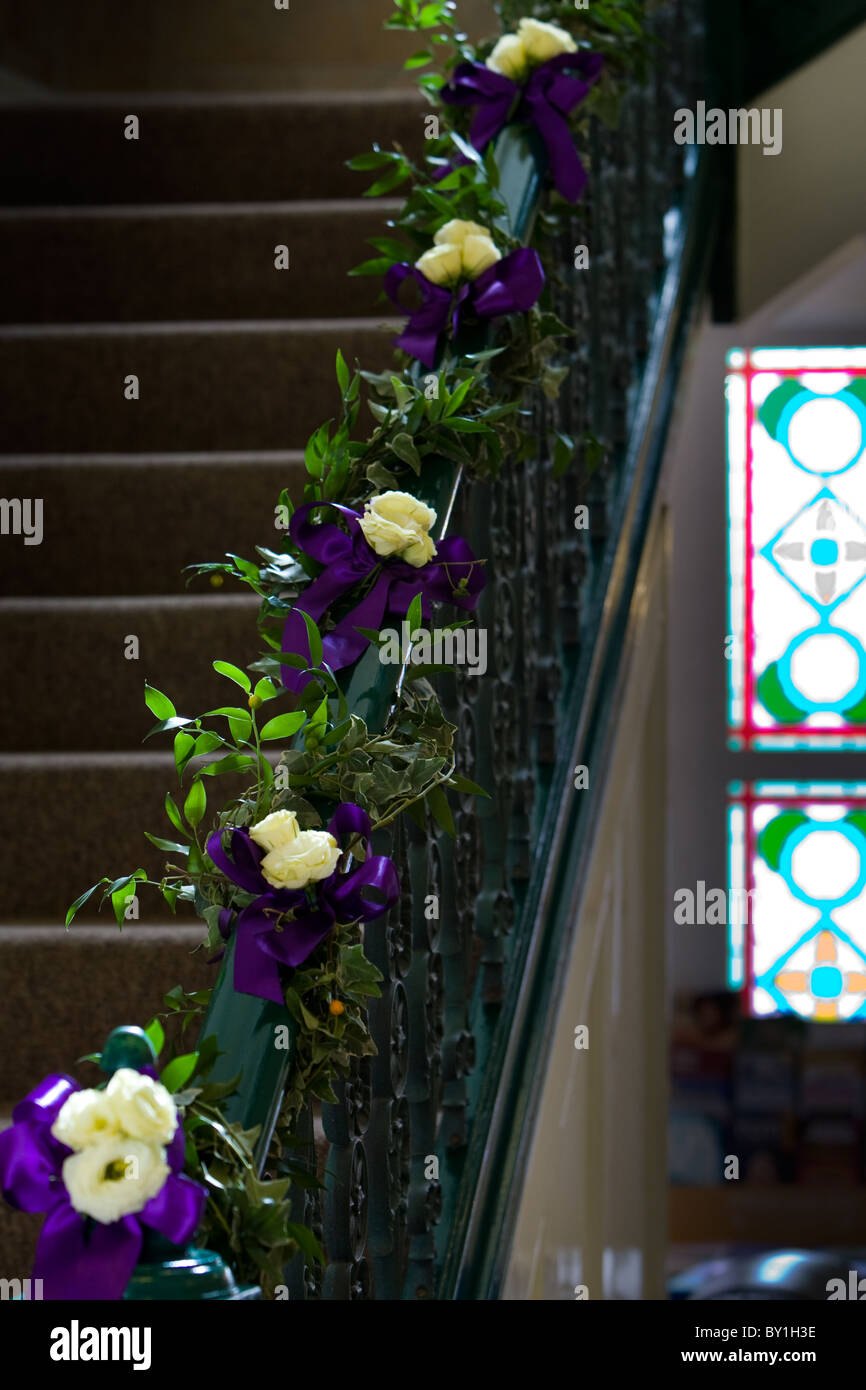 cremefarbene Rosen mit lila Band auf Treppengeländer Stockfoto