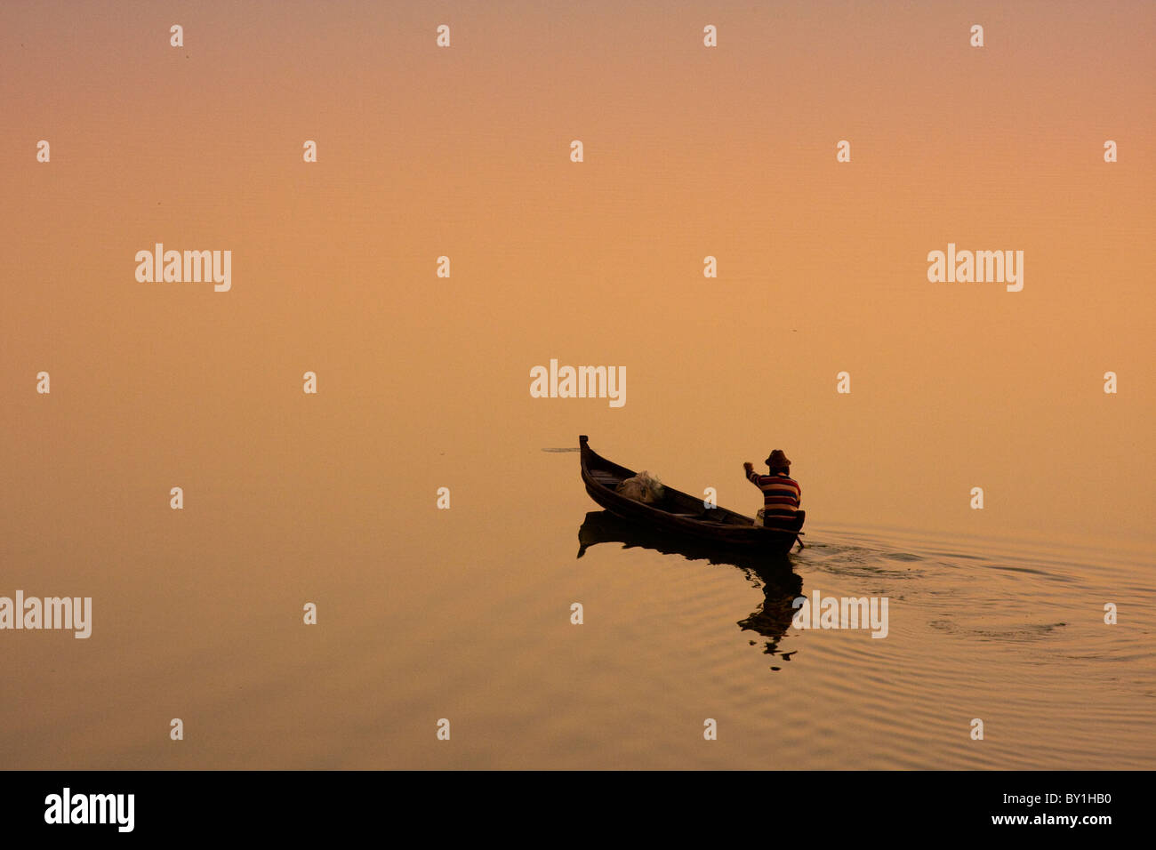 Myanmar, Burma, Amarapura. Ein Fischer bei Sonnenaufgang, Amarapura über Taungthaman See paddeln. Stockfoto