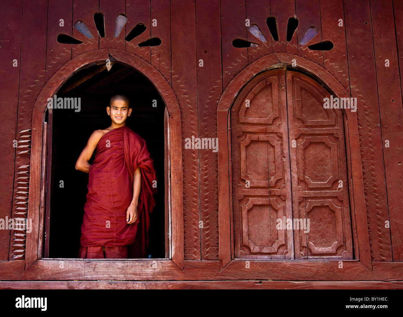 Myanmar, Burma, Nyaungshwe.  Ein junger Novize am ein Holzfenster, Shwe Yaunghwe Kyaung Kloster stehen. Stockfoto