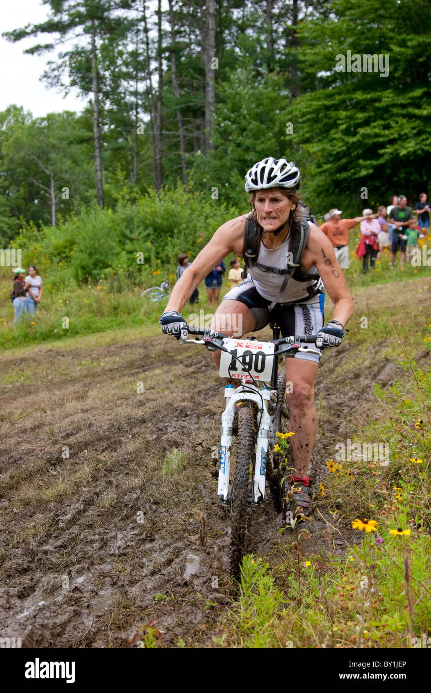 Weibliche Mountain Racer Fahrradpedale über schlammigen Pfad während der Off-Road-Triathlon-Renn-event Stockfoto