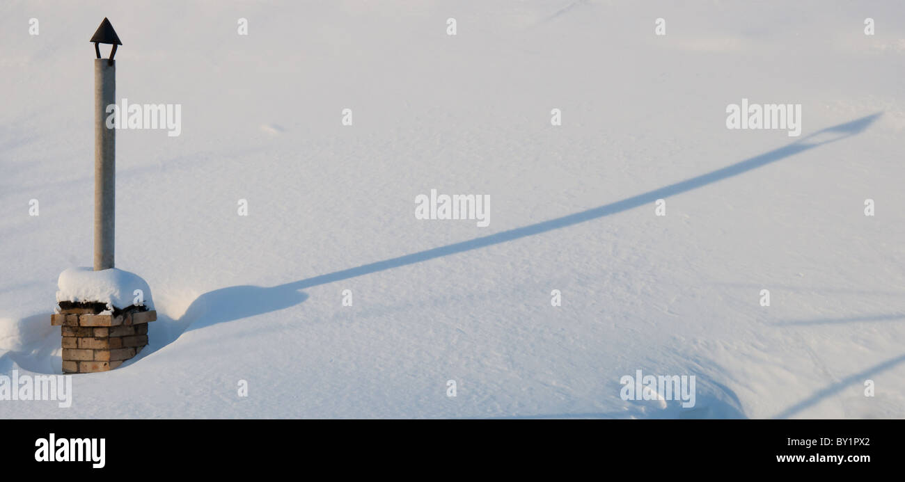 Rauchfang und Schatten auf dem verschneiten Winter-Dach Stockfoto