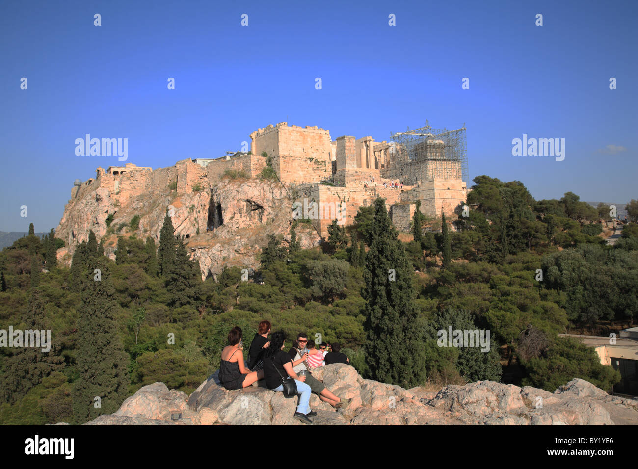 Junge Leute sitzen am späten Nachmittag mit Blick auf den Hügel der Akropolis von Athen oder Zitadelle von Athen Athen, Griechenland Stockfoto