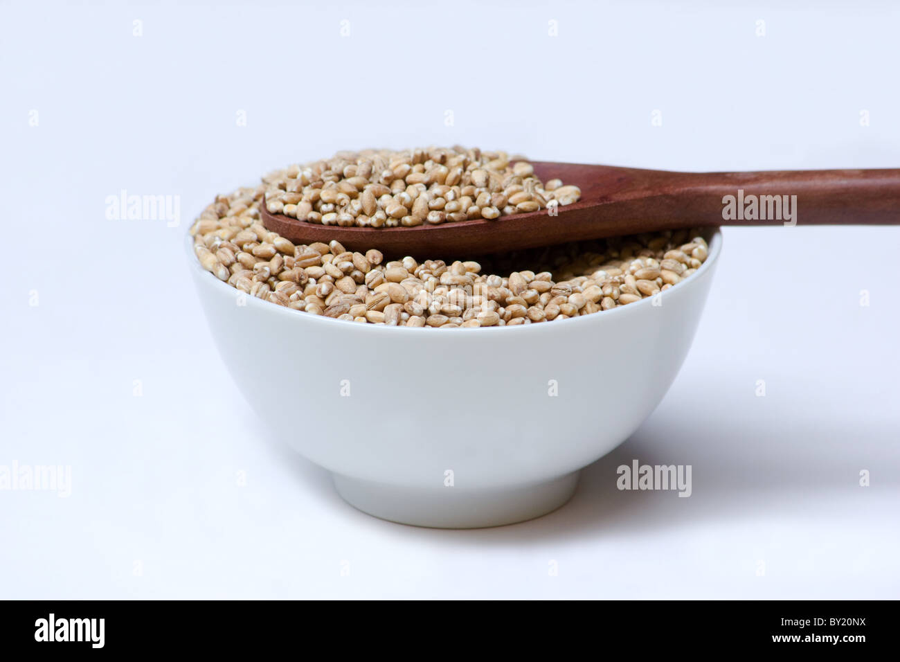 Nahaufnahme einer Schüssel Gerste mit einem Holzlöffel Stockfoto