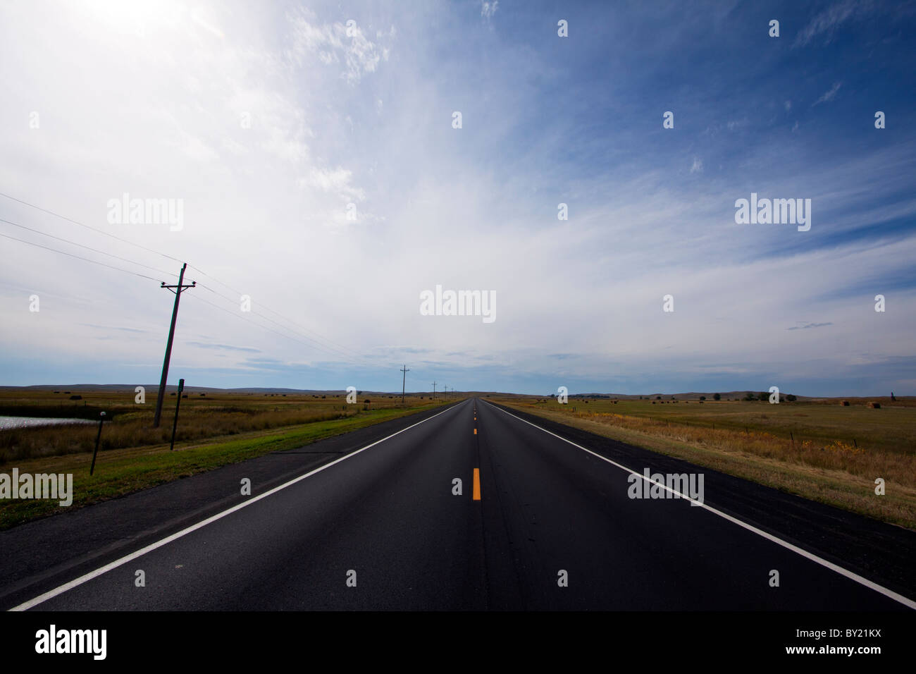 Eine einsame Straße erstreckt sich bis zum Horizont als Gewitterwolken Ansatz über die Ebenen des mittleren Westens. Stockfoto