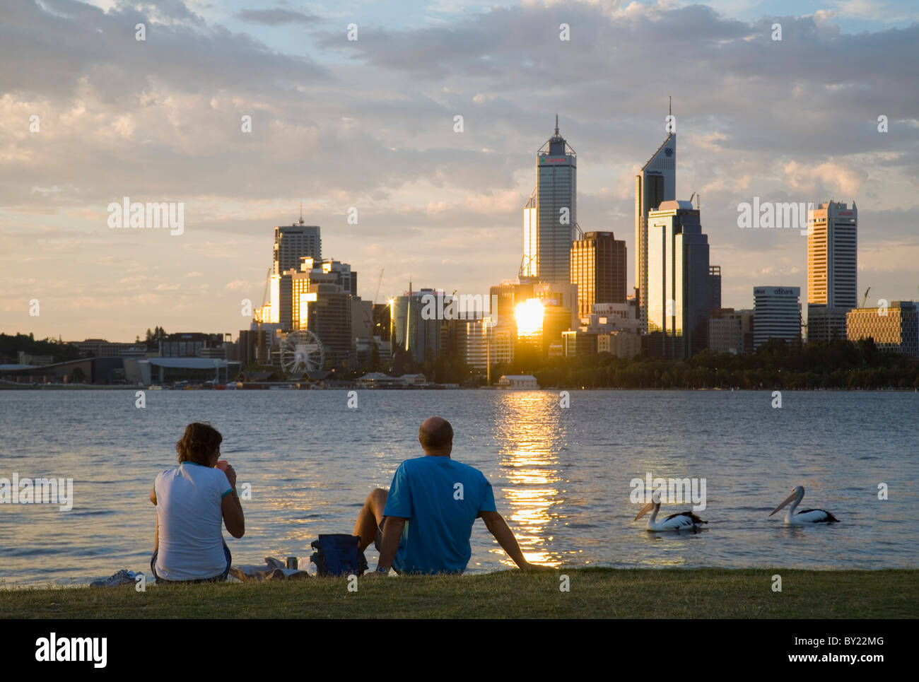 Australien, Western Australia, Perth, South Perth.  Ein paar freuen sich über den Swan River auf die Skyline der Stadt in der Dämmerung. Stockfoto