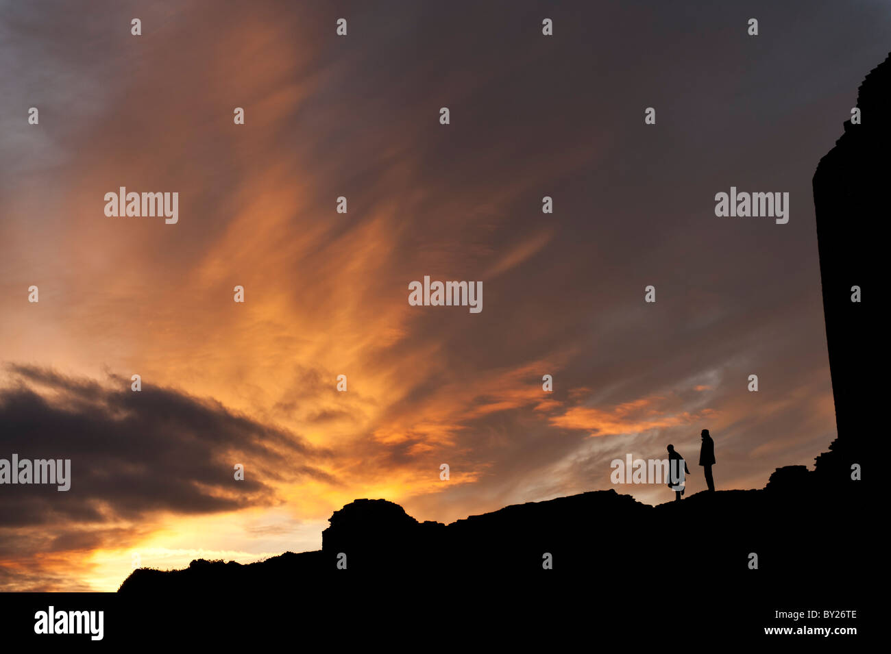 zwei Menschen stehen in Silhouette in vor einem dramatischen Himmel und Wolken bei Sonnenuntergang Dämmerung, UK Stockfoto