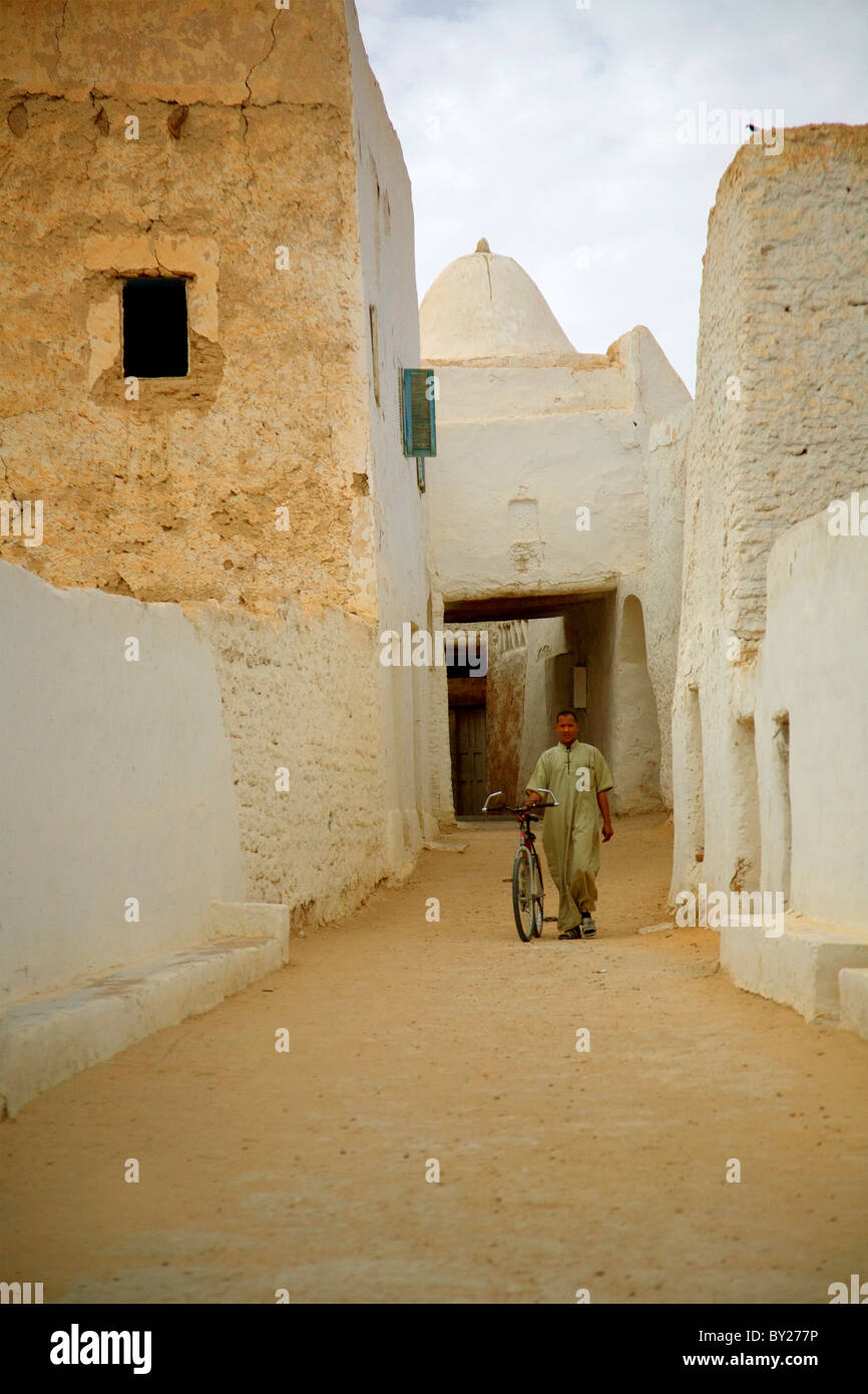 Ghadames, Libyen; Ein Mann geht mit seinem Fahrrad durch einzigartige Schlamm errichtet Gebäude von der Oase alte Stadt Ghadames Stockfoto