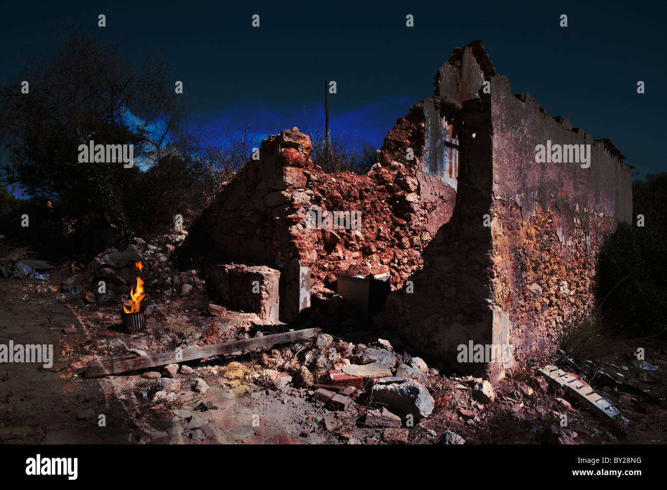 Gruseligen verlassenen verfallenden Gebäude in der Nacht mit einem Feuer in einem Metallkorb. Stockfoto