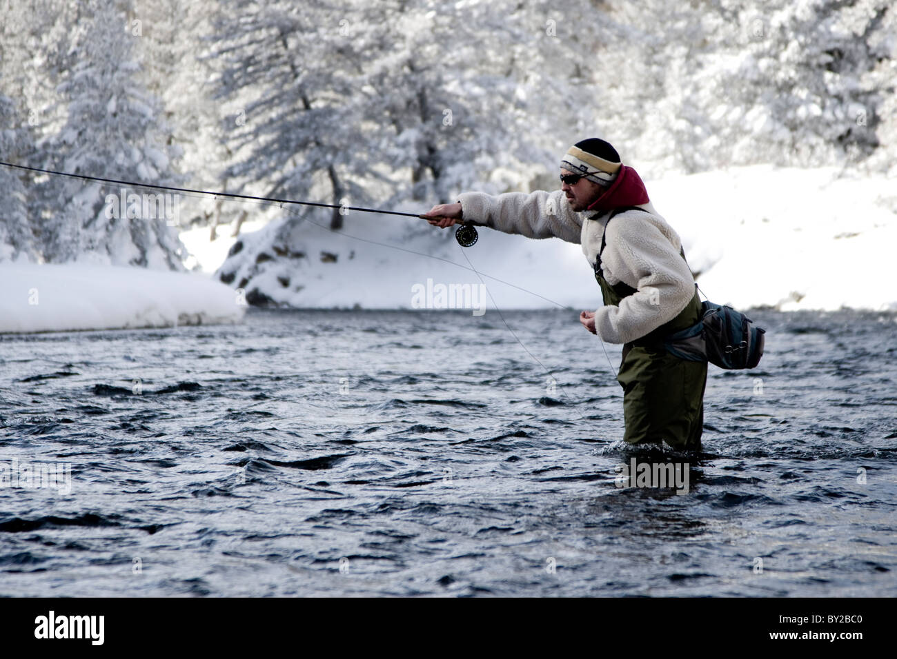 Ein Fliegenfischer im Fluss stehend, an einem Wintertag. Stockfoto