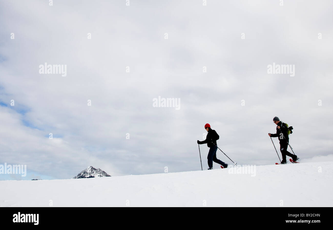 Zwei Menschen, Schneeschuhwanderung entlang einer Kante an einem bewölkten Tag. Stockfoto