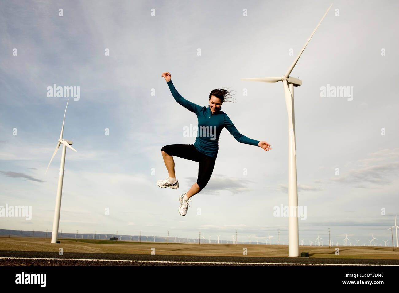 Eine Frau mit Windmühlen im Hintergrund in die Luft springen. Stockfoto