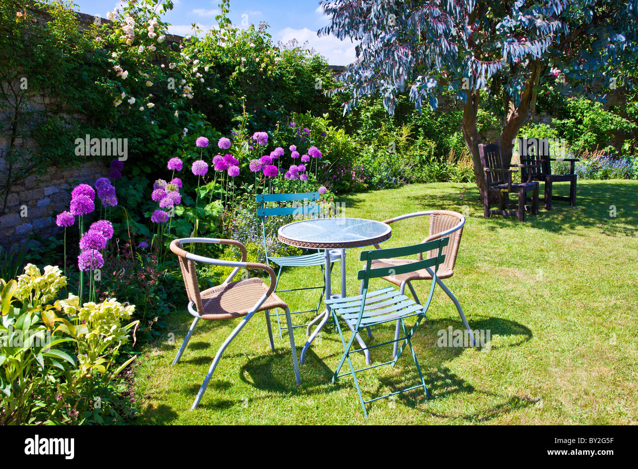 Tisch und Stühle auf dem Rasen in einen ummauerten englischen Country-Sommergarten Stockfoto