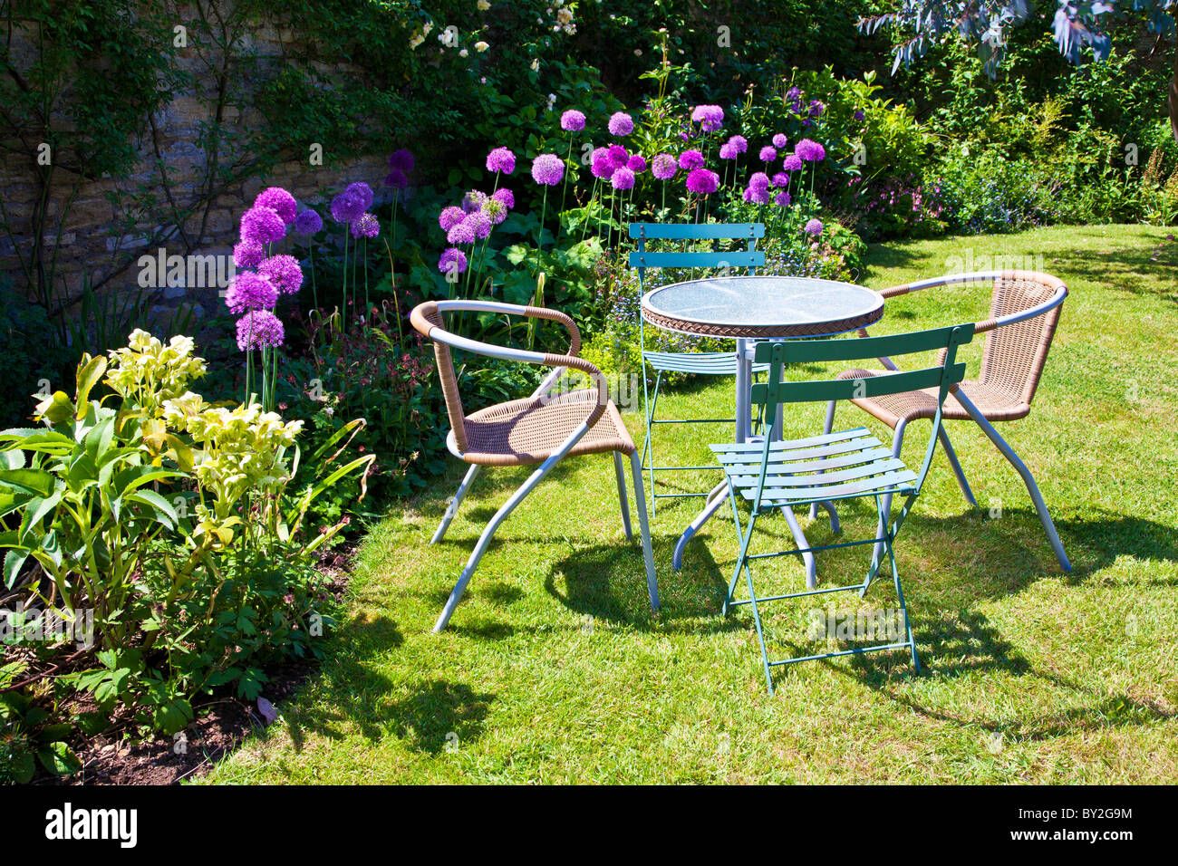 Tisch und Stühle auf dem Rasen in einen ummauerten englischen Country-Sommergarten Stockfoto
