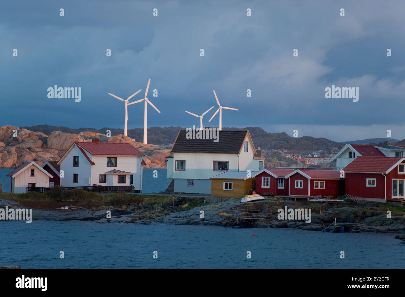 Gebäude auf der Insel Kladesholmen, (auch bekannt als Hering Insel) Schweden. mit windbetriebenen Turbinen im Hintergrund. Stockfoto
