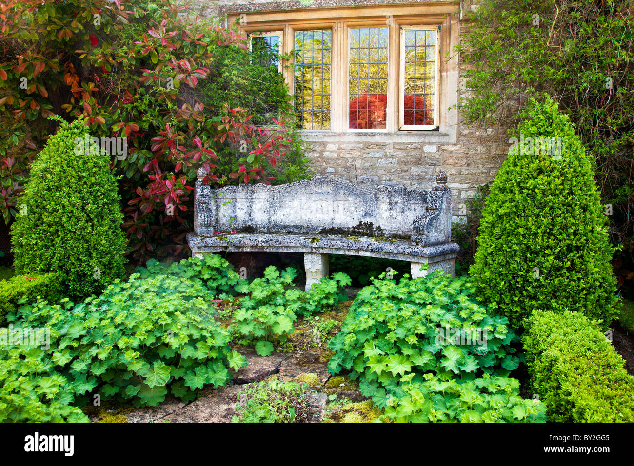 Eine Steinbank unter einer zweibogigen Fenster in einer abgelegenen Ecke des einen englischen Country-Sommergarten Stockfoto