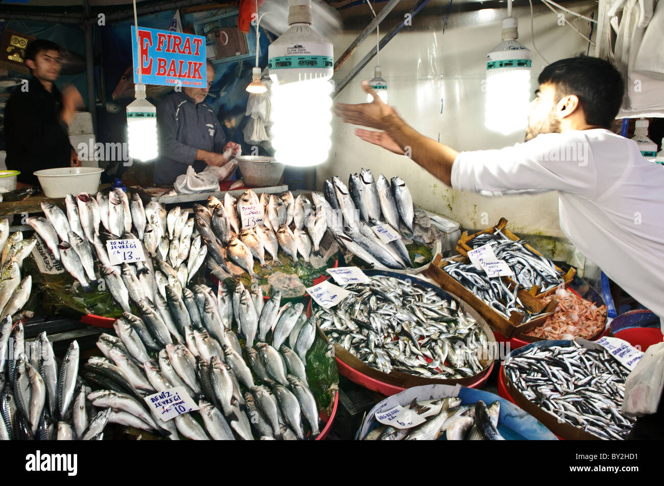 ISTANBUL, Türkei – Ein Verkäufer fängt ein Paket Fisch, das sein Kollege auf dem Karakoy Fischmarkt in der Nähe der Galata-Brücke in Istanbul geworfen hat. Diese traditionelle Marktpraxis demonstriert die fachkundige Koordinierung zwischen Arbeitnehmern, die frische Meeresfrüchte aus dem Bosporus und den nahe gelegenen Gewässern handhaben. Stockfoto