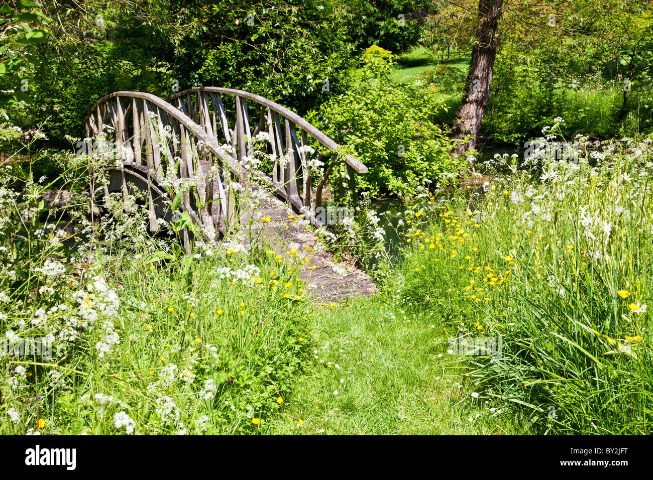 Eine charmante rustikale Fußgängerbrücke in einer ruhigen Ecke von einem englischen Landhaus-Garten im Sommer Stockfoto