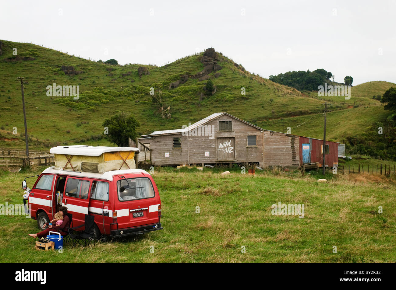 Eine Mutter und Tochter sitzen Sie draußen ihre Wohnmobil beim Parken in der Nähe von einem alten Scheren Schuppen in Neuseeland. Stockfoto