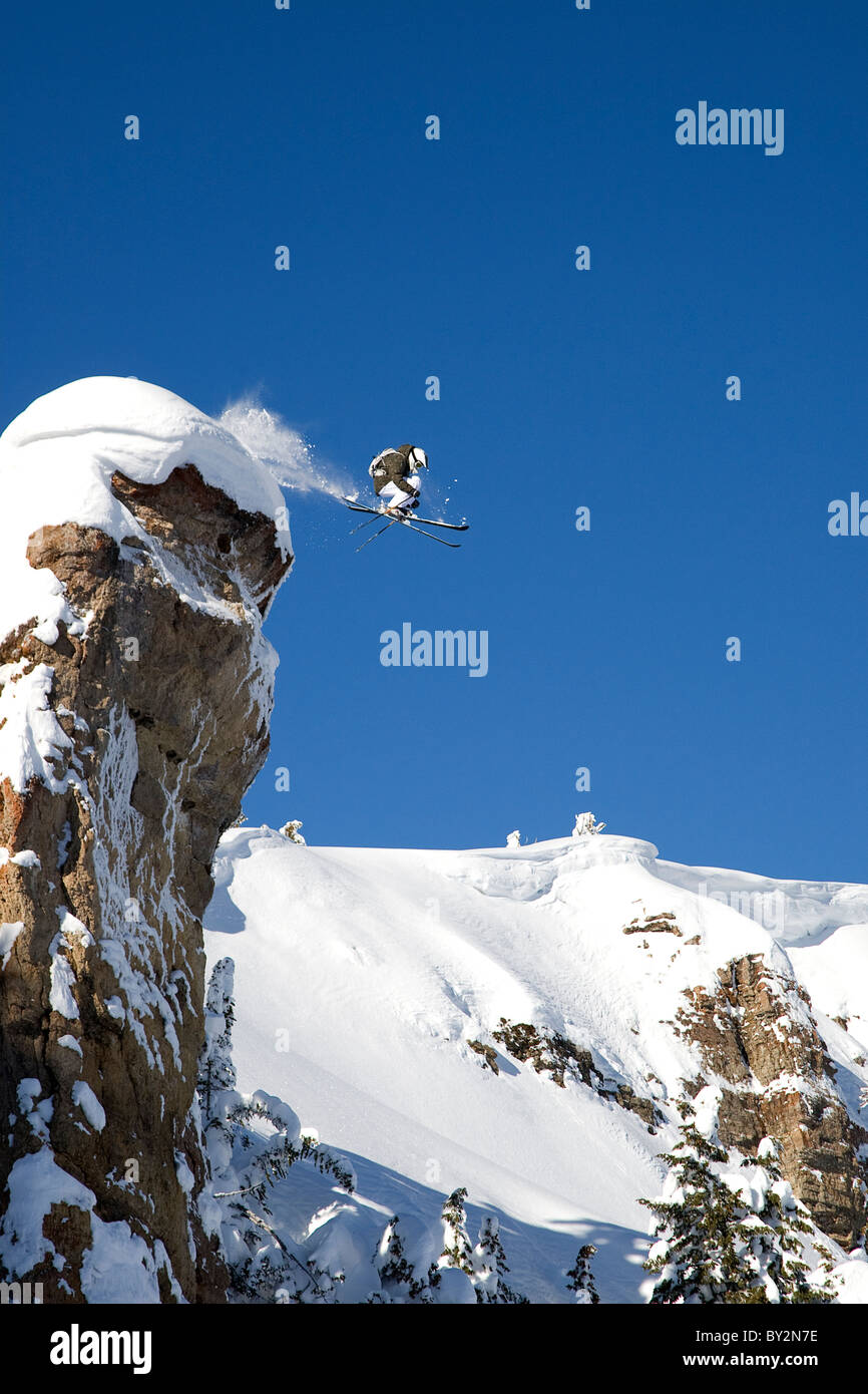 Ein männlicher Skifahrer springt eine 100 Fuß hohen Klippe, bekannt als das Sprungbrett in die Grand Targhee Backcountry, Wyoming. Stockfoto