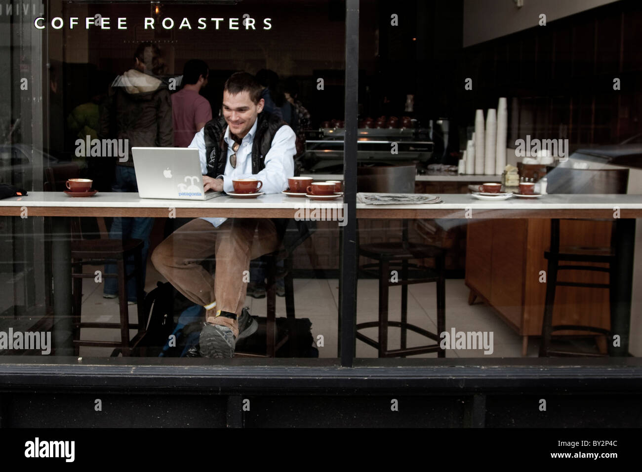 Ein Mann, der durch das Fenster von einem Coffee-Shop arbeitet an seinem Laptop zu sehen. Stockfoto