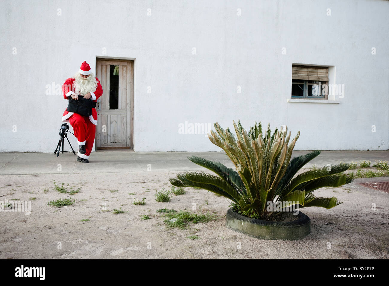 Ein Mann gekleidet wie Santa Claus seine Aktentasche neben einer Tür öffnet. Rocha, Uruguay Stockfoto