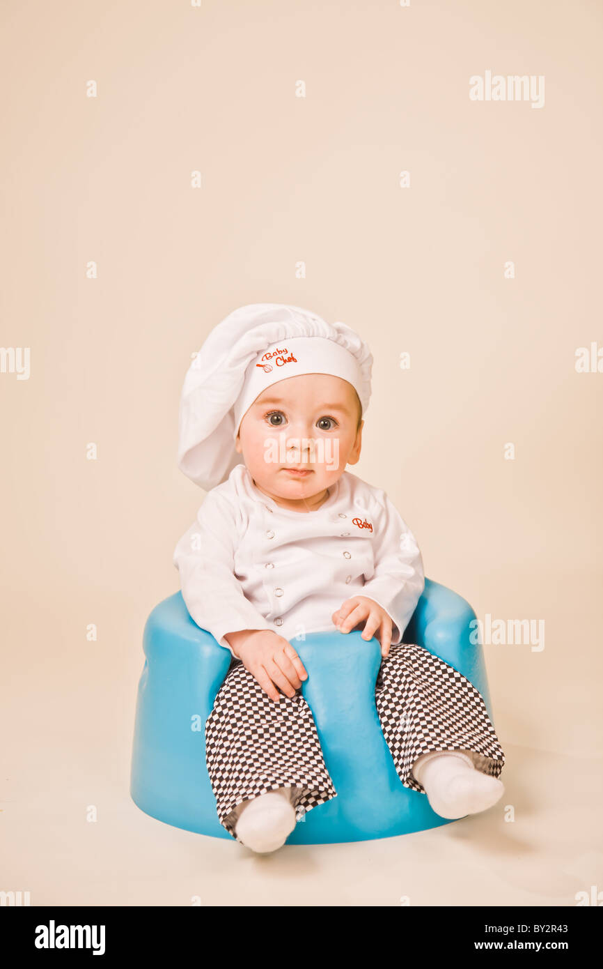 Baby-Chef sitzt in einem blauen Stuhl Stockfoto