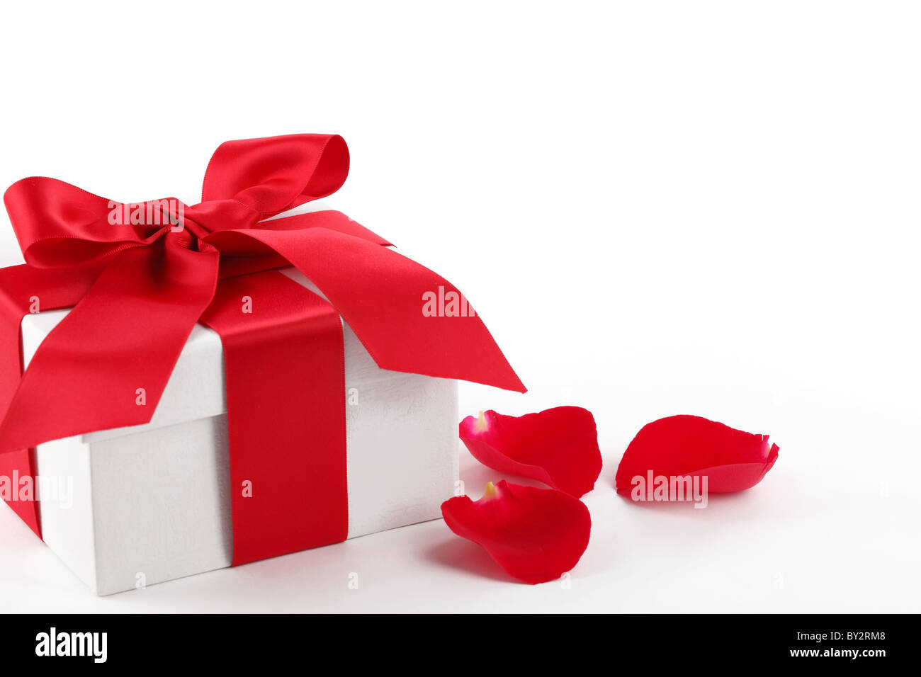 Geschenk-Box und Rosenblättern auf weißem Hintergrund. Stockfoto