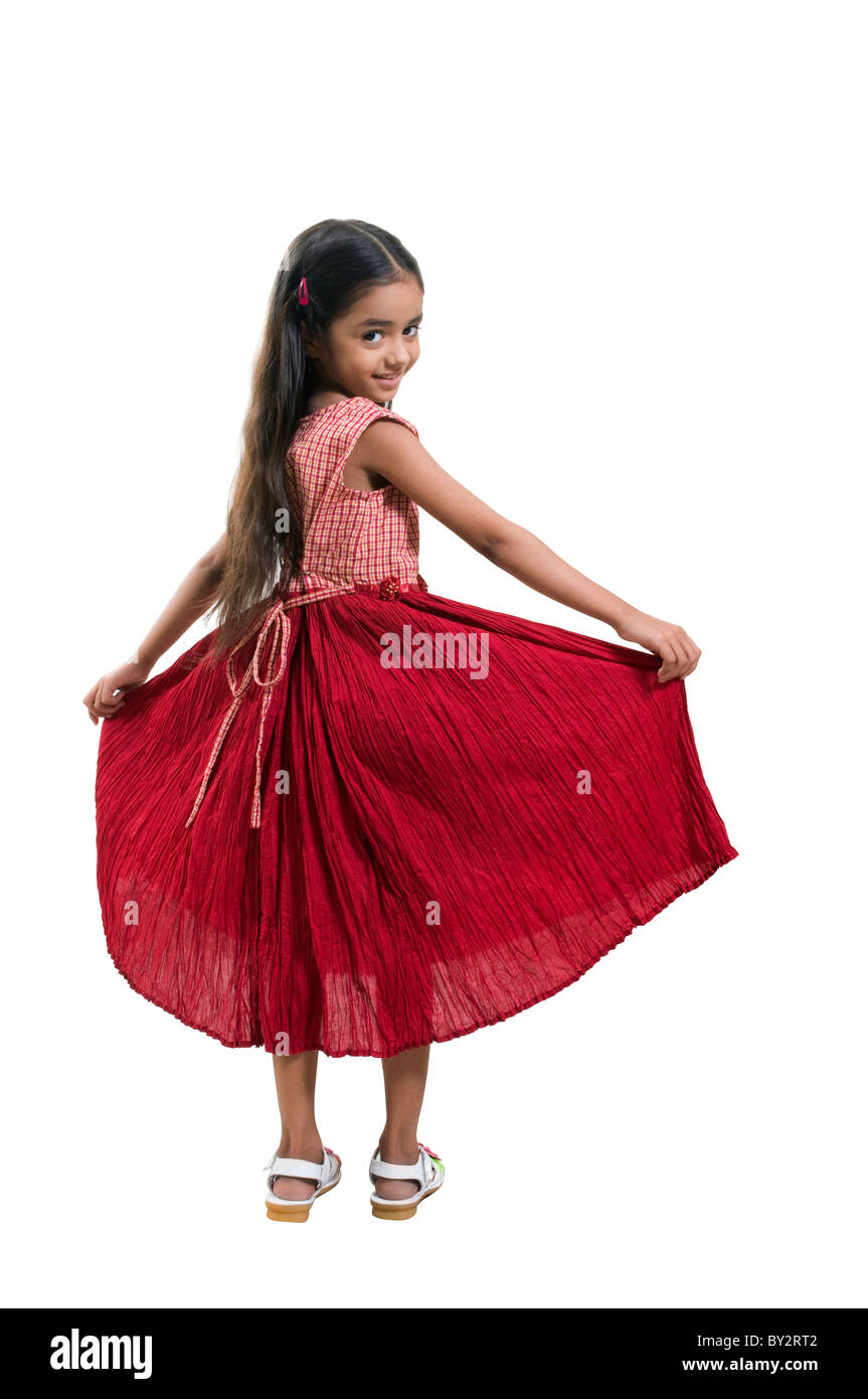 kleine Mädchen stehen und halten ihr Kleid Stockfoto