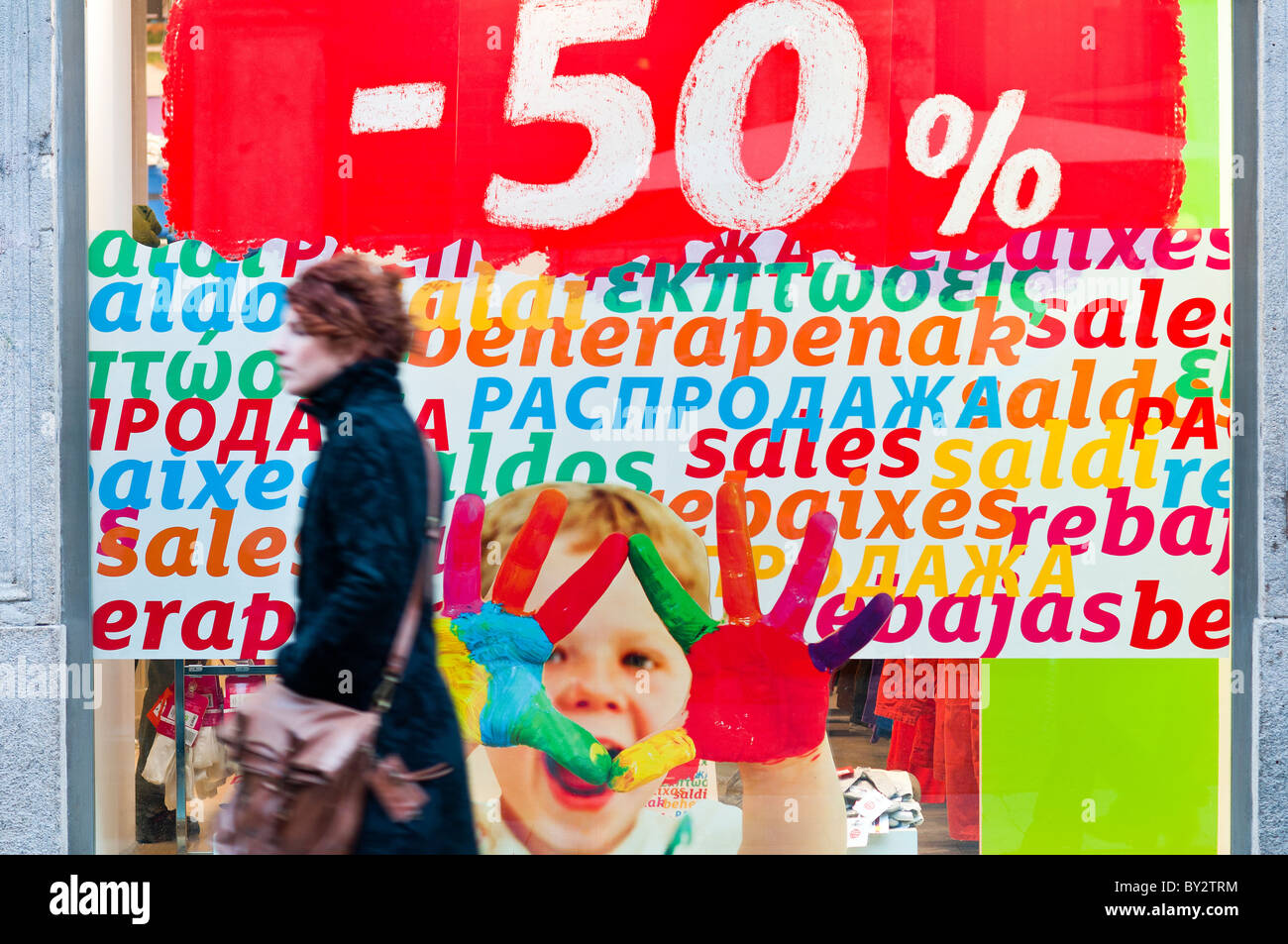 Mann beobachtet ein Mode-Schaufenster mit mehrsprachigen Verkaufsposter, Mailand, Italien Stockfoto