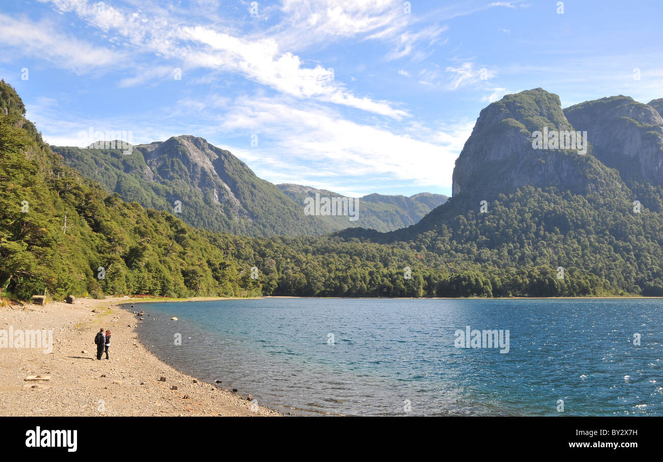 Blick auf den blauen See Brazo gesegnet, gemäßigten valdivianischen Regenwald und Granit Zinnen, mit zwei Personen an einem Strand, Anden, Argentinien Stockfoto