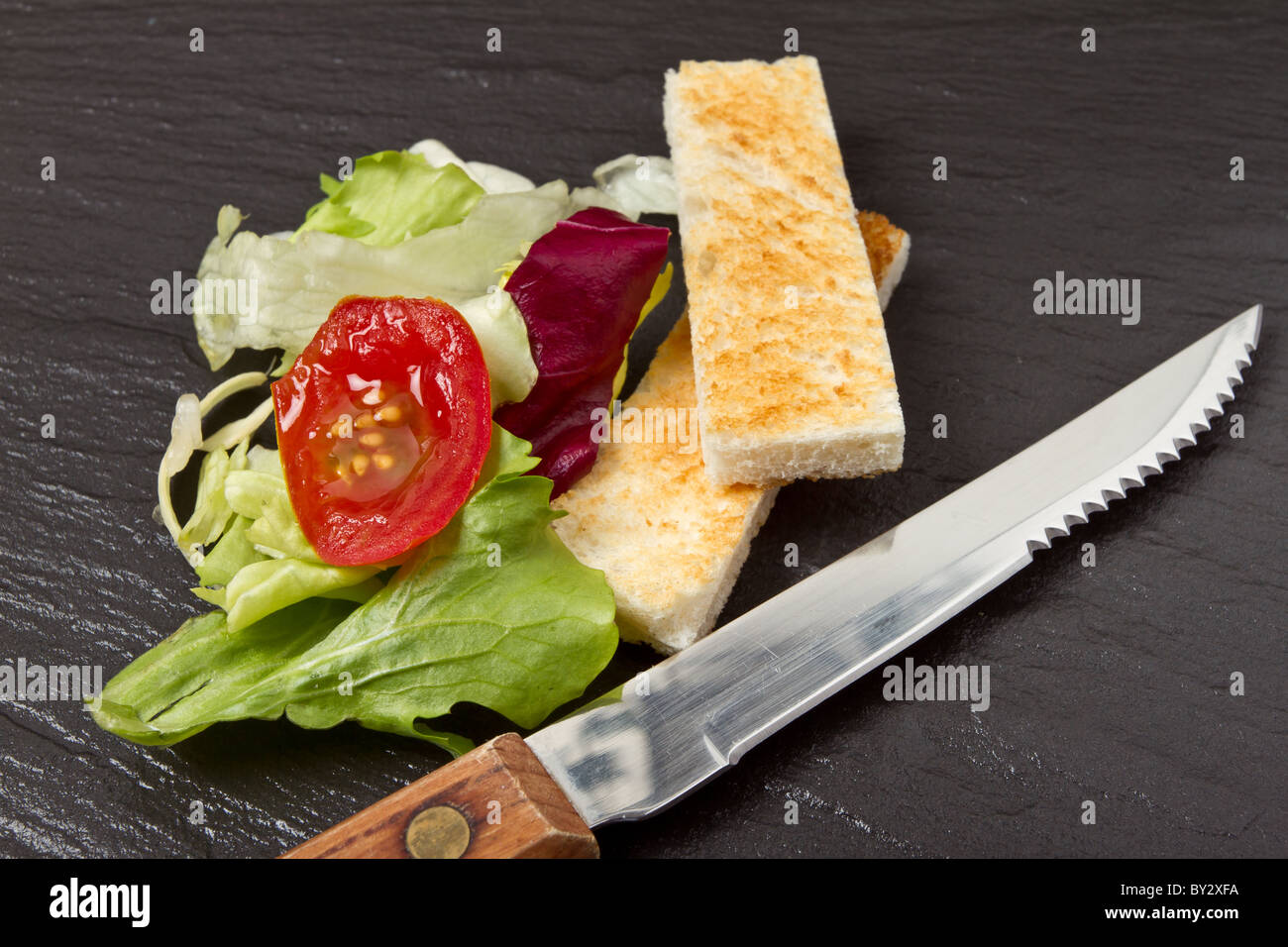 Apetiser Pastete mit Melba Toast Soldaten und kleinem Salat auf dunklem Schiefer. Stockfoto