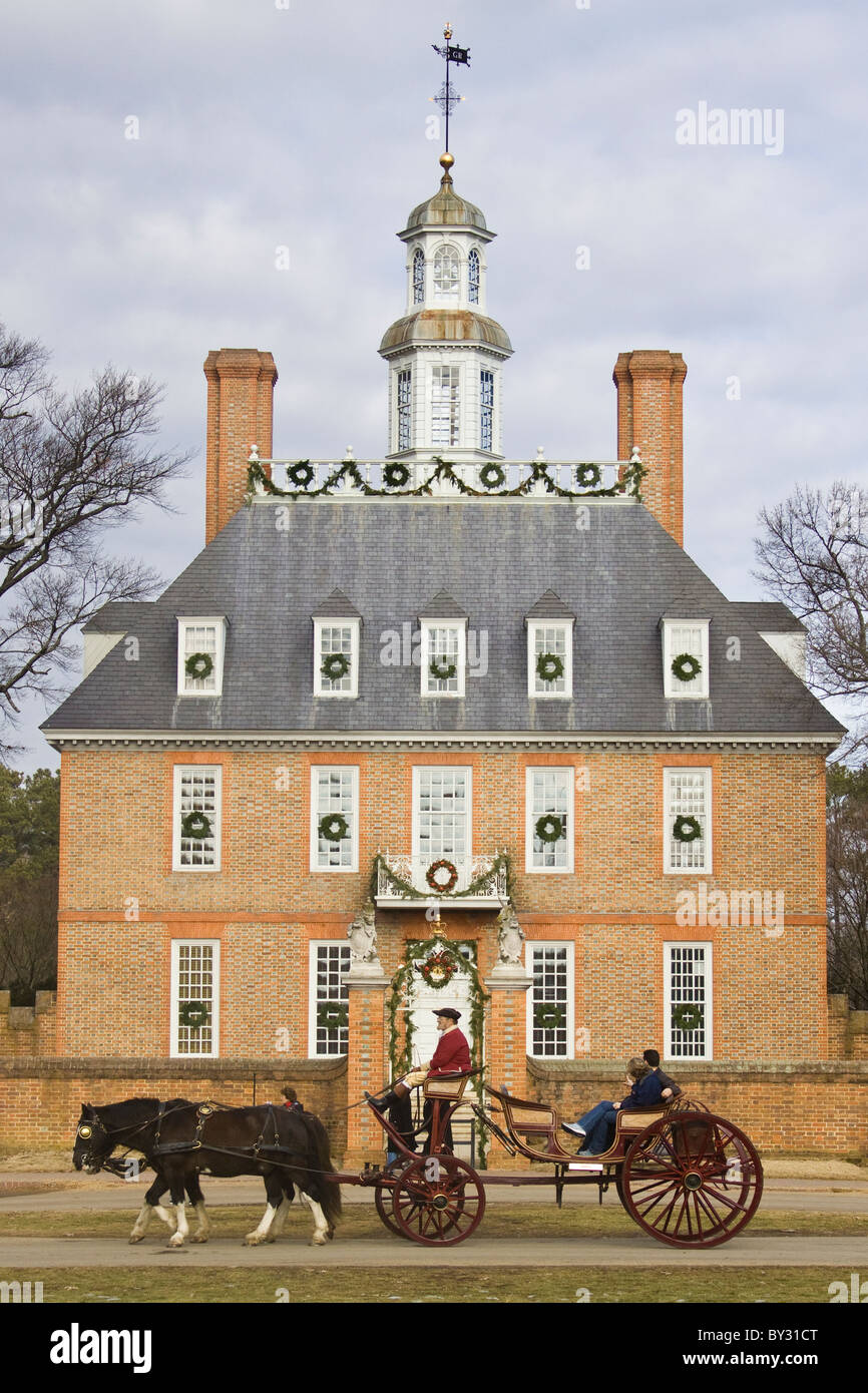 Kutscher und Touristen fahren durch den Gouverneurspalast, geschmückt mit Weihnachtsschmuck in historischen Colonial Williamsburg, VA. Stockfoto