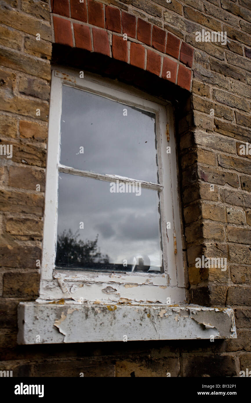 Ein Fenster an der Seite eines Hauses in einem schlechten Zustand Stockfoto