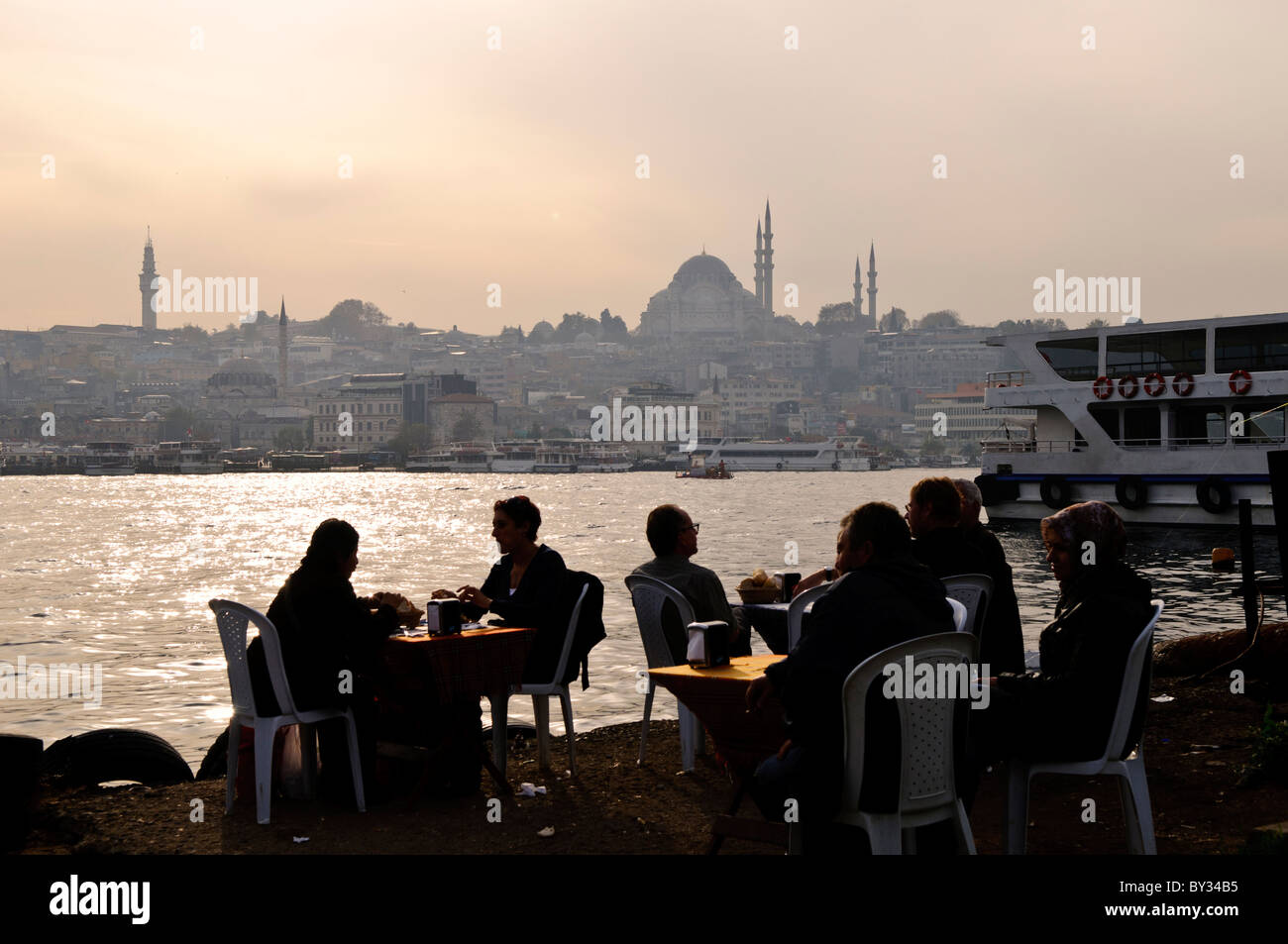 Suleymaniye-Moschee vom Karakoy Fish Market Istanbul // ISTANBUL, Türkei – die Gäste genießen eine Mahlzeit in einem Fischrestaurant neben dem Karakoy Fish Market in der Nähe der Galata Brücke. Die historische Suleymaniye-Moschee, die 1557 fertiggestellt wurde, dominiert die Skyline über den Wasserweg des Goldenen Horns. Die Moschee, die größte des Osmanischen Reiches, ist ein Beispiel für die klassische osmanische Architektur. Stockfoto