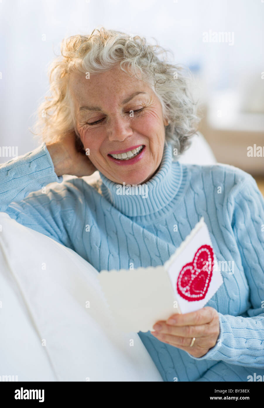 USA, New Jersey, Jersey City, Senior Woman Valentines Karte im Wohnzimmer lesen Stockfoto