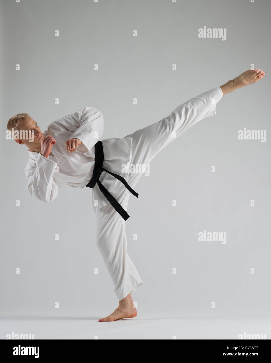 Junger Mann, die Durchführung von Karate Kick auf weißem Hintergrund Stockfoto