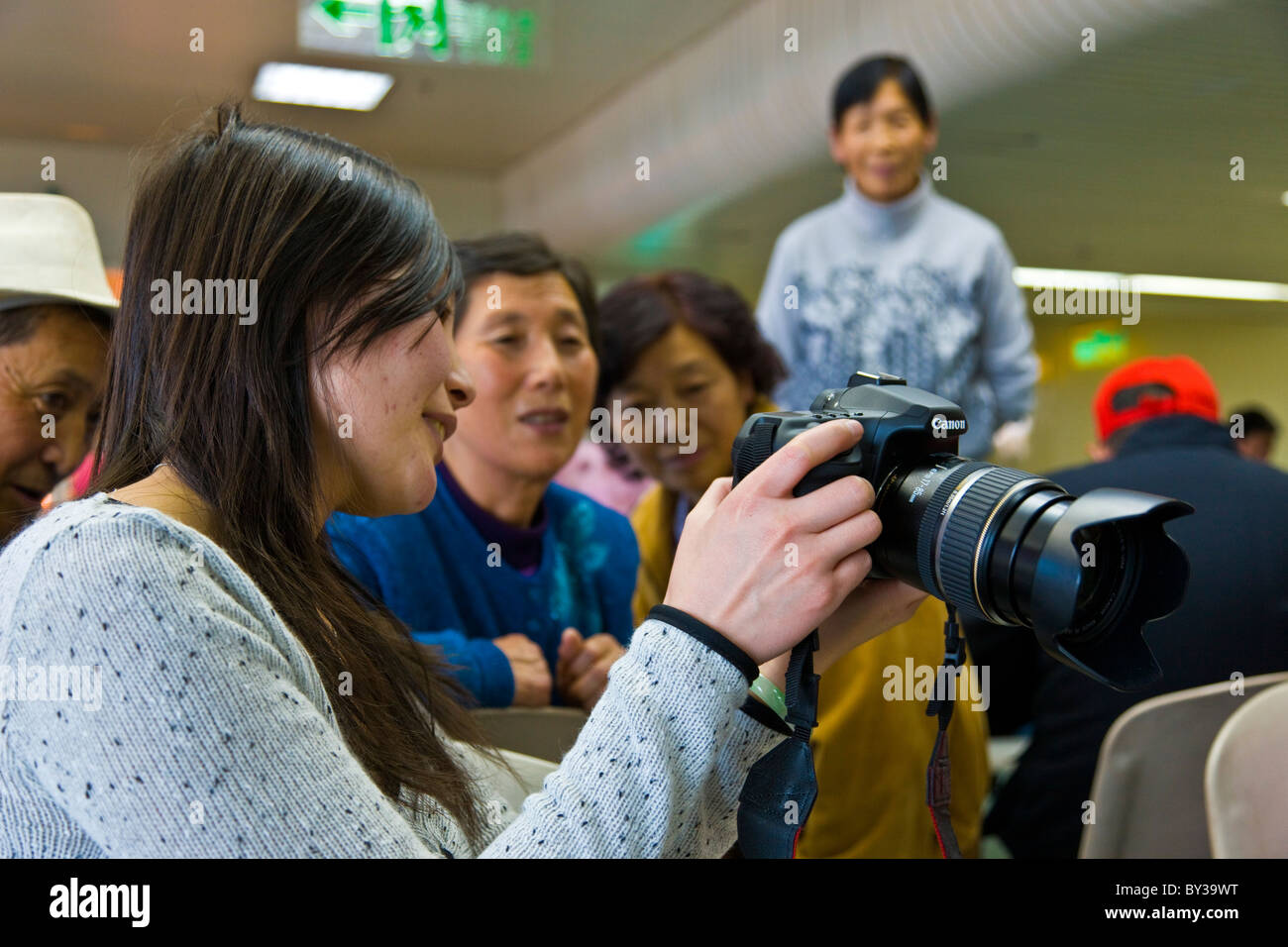 Chinesische Frau zeigt Bilder auf dem Bildschirm auf ihre Canon digital Spiegelreflexkamera am Flughafen Guangzhou China. JMH4167 Stockfoto