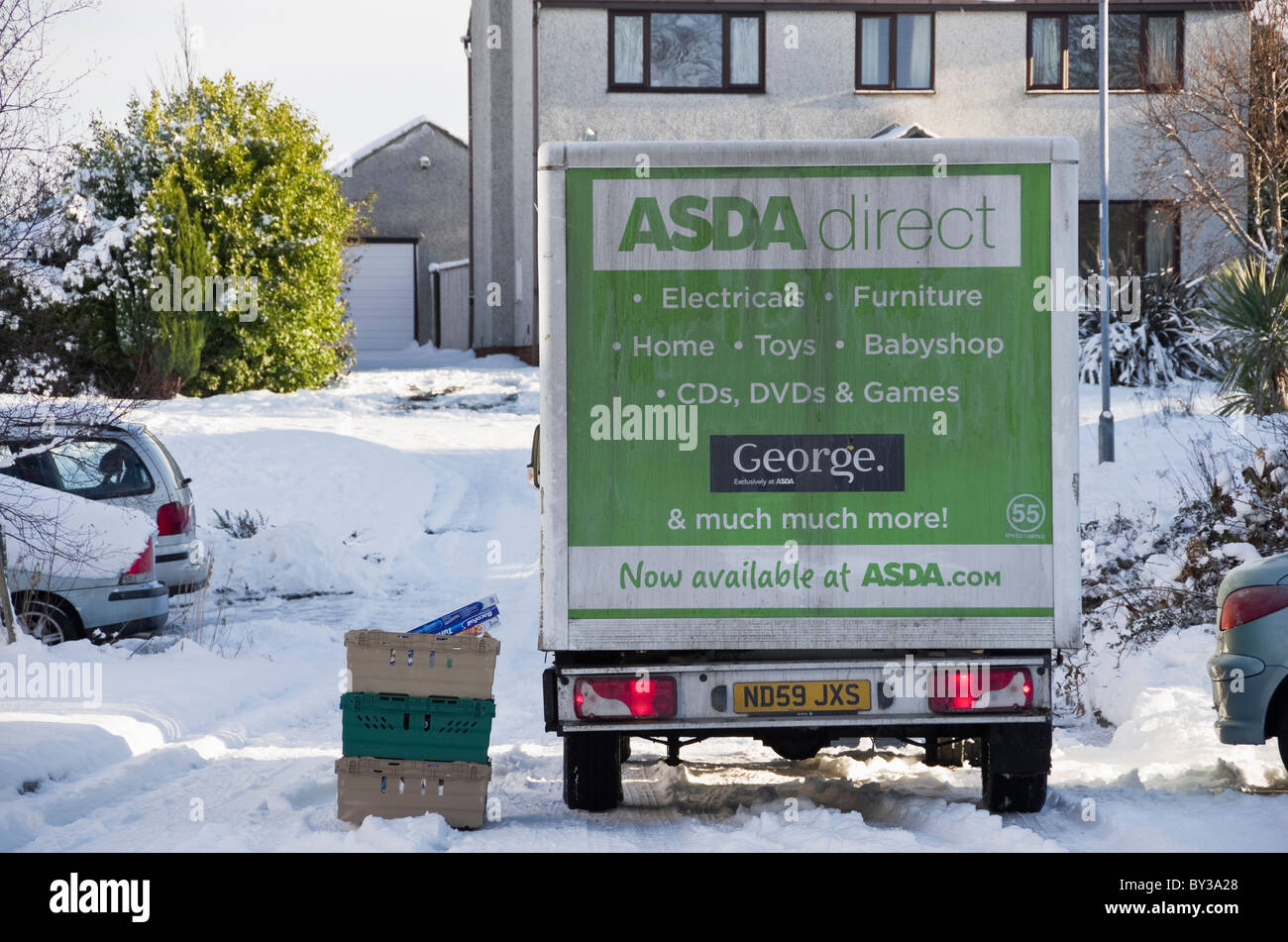 UK, Großbritannien. ASDA Hause Lieferwagen vor einem Haus liefern, Online-shopping mit Schnee in Wohnstraße im winter Stockfoto