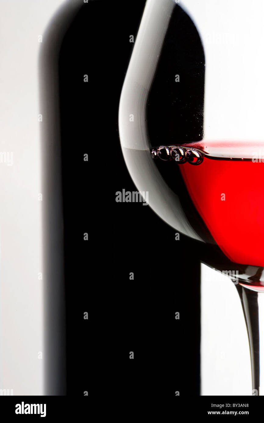 Stilleben mit Flasche und Glas Rotwein auf weißem Hintergrund. Stockfoto