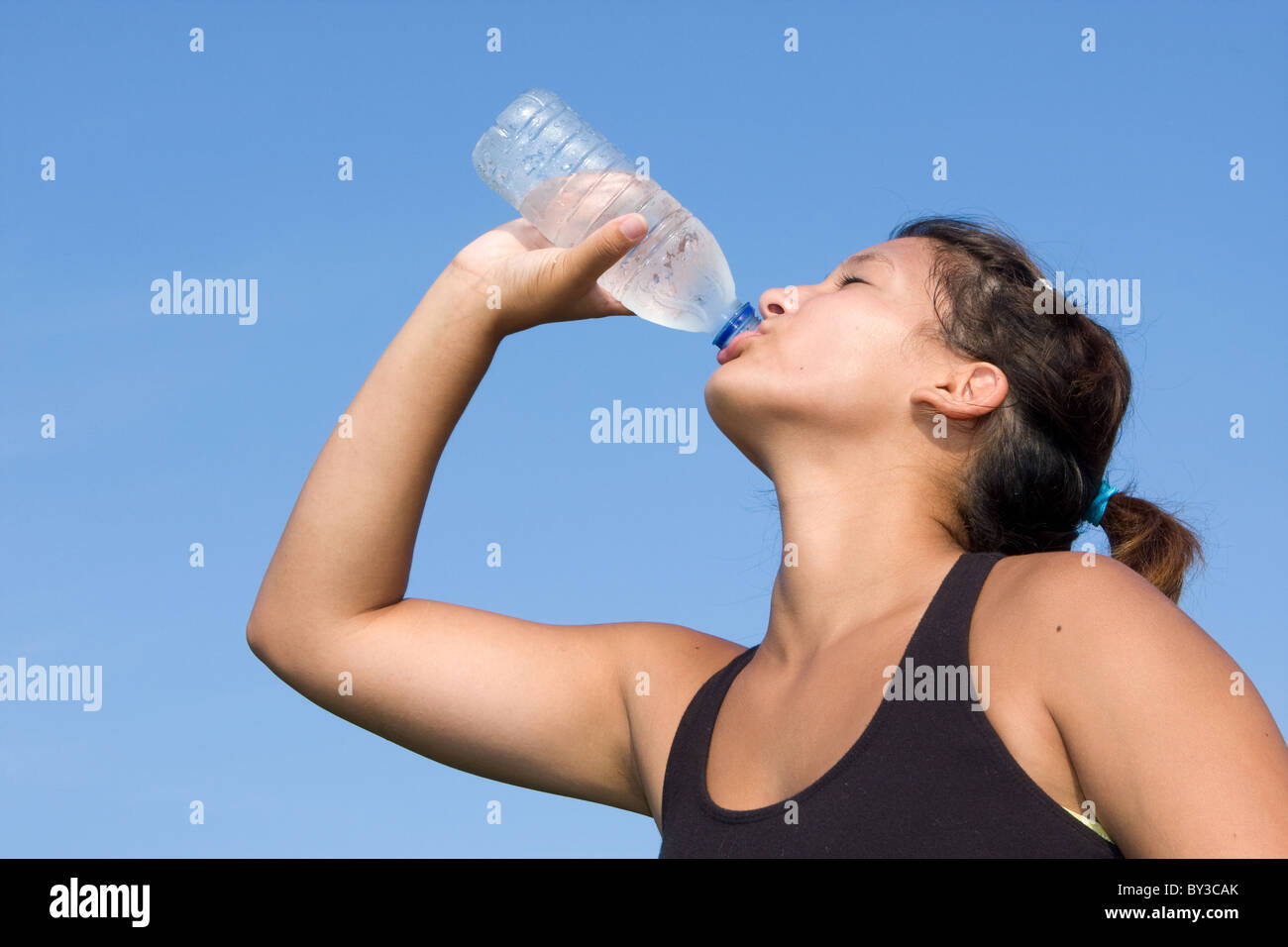 Junge Sportler trinkt Wasser aus einer durchsichtigen Kunststoff-Flasche nach einer laufenden Übung in ein outdoor-Strecke. Stockfoto