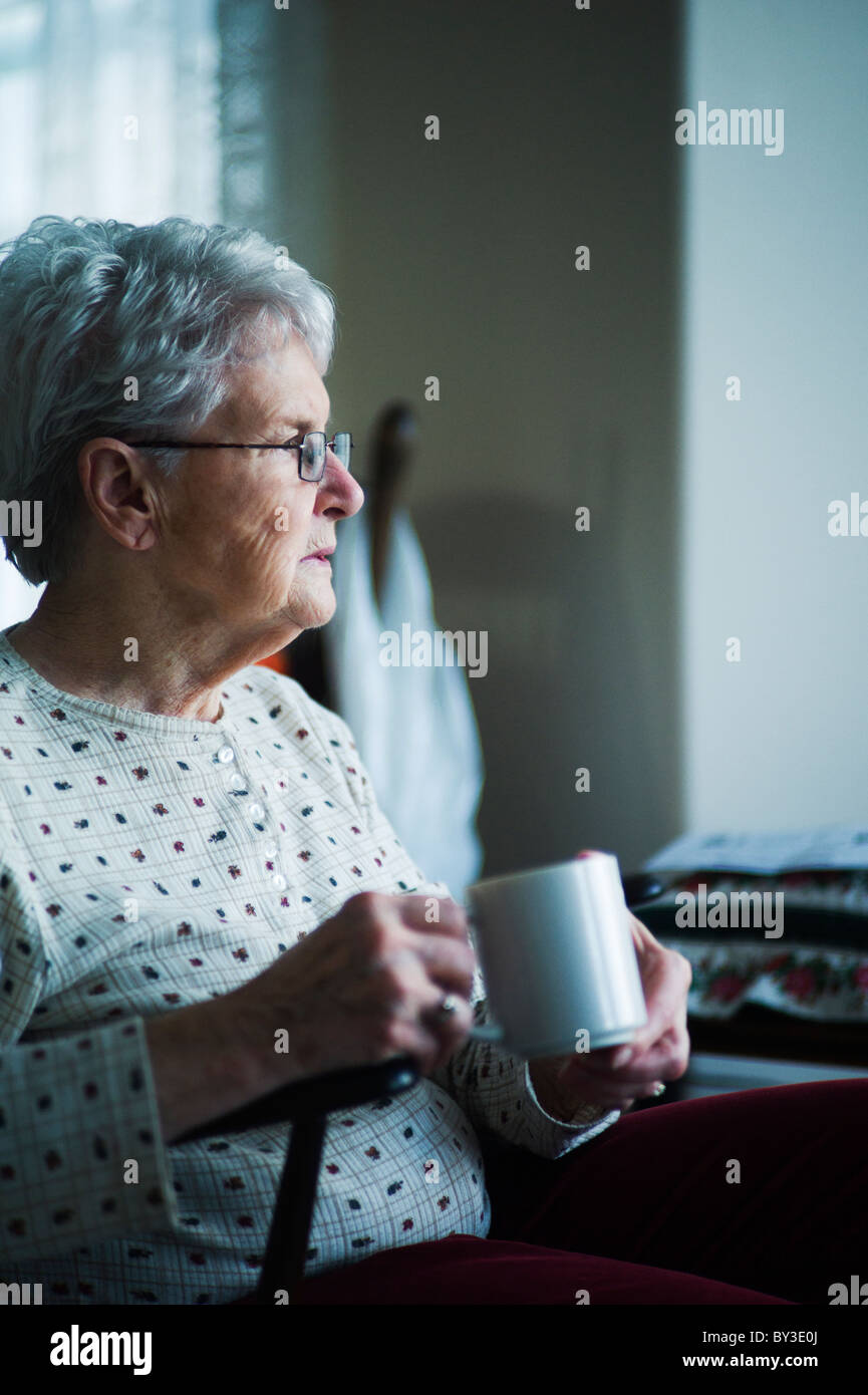 Alte Frau sitzen auf Stuhl mit Tasse Tee. Stockfoto